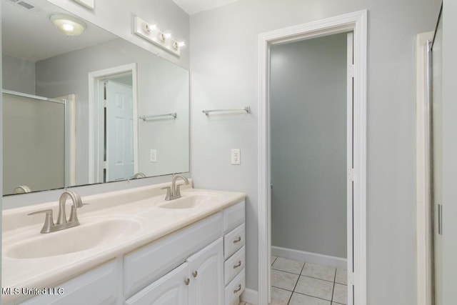 full bathroom with a shower stall, double vanity, tile patterned flooring, and baseboards