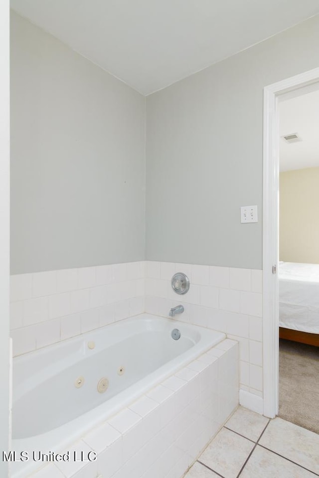 ensuite bathroom featuring a whirlpool tub and tile patterned flooring