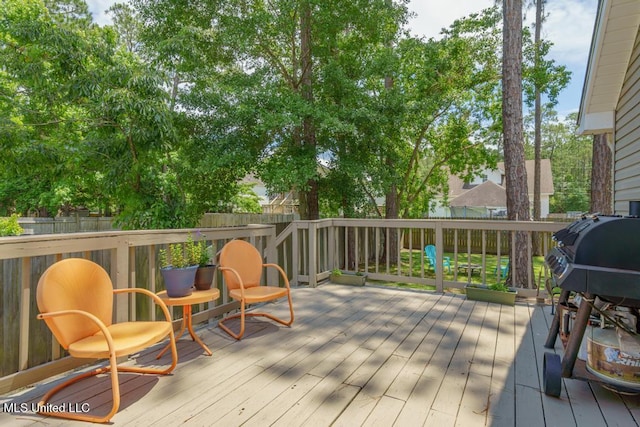wooden deck with a fenced backyard and area for grilling