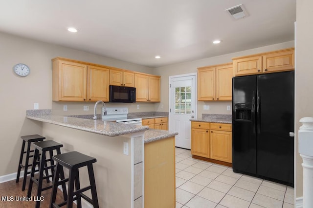kitchen with black appliances, light brown cabinets, a peninsula, a breakfast bar area, and recessed lighting