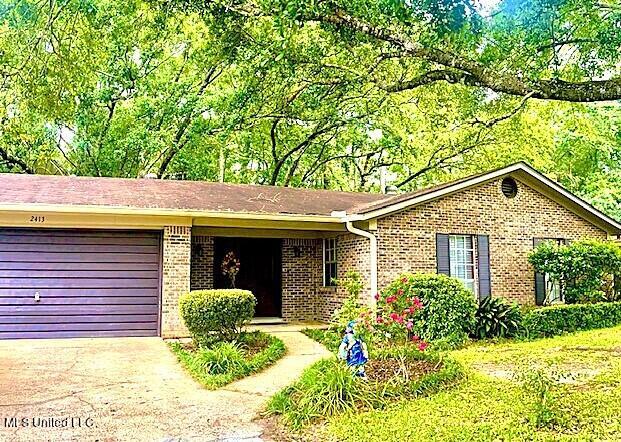 single story home with concrete driveway, brick siding, and an attached garage