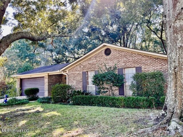 single story home featuring a garage, a front yard, and brick siding