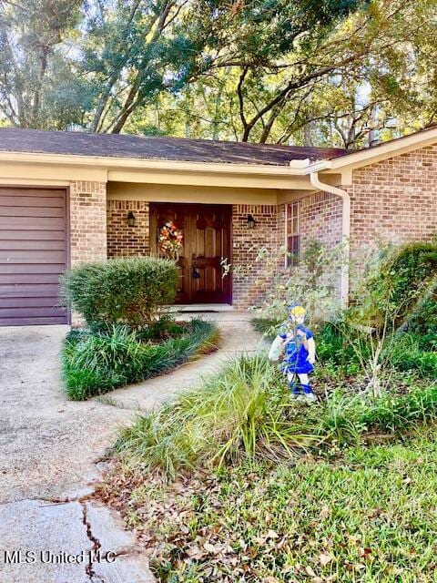 view of exterior entry with brick siding and an attached garage