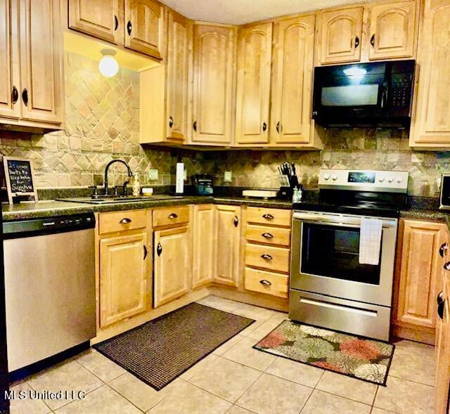 kitchen featuring appliances with stainless steel finishes, backsplash, light tile patterned floors, and sink