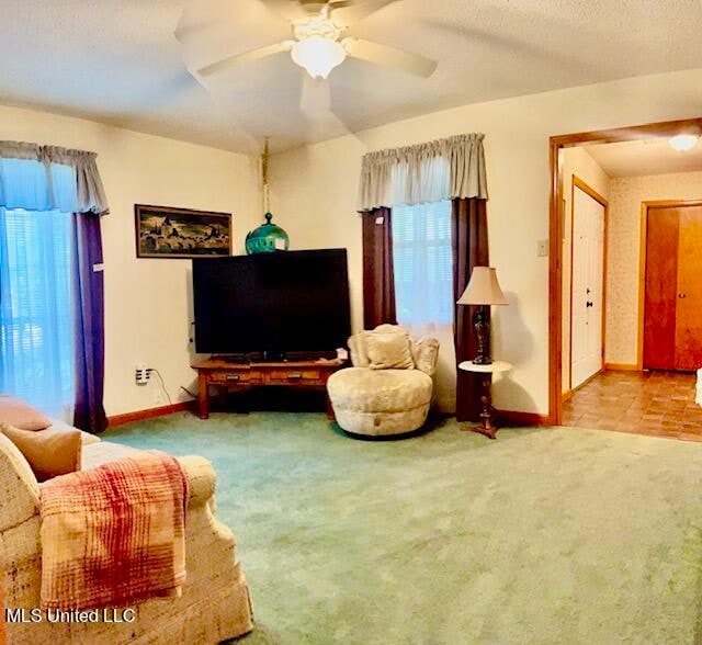 living room featuring light carpet, ceiling fan, and a textured ceiling