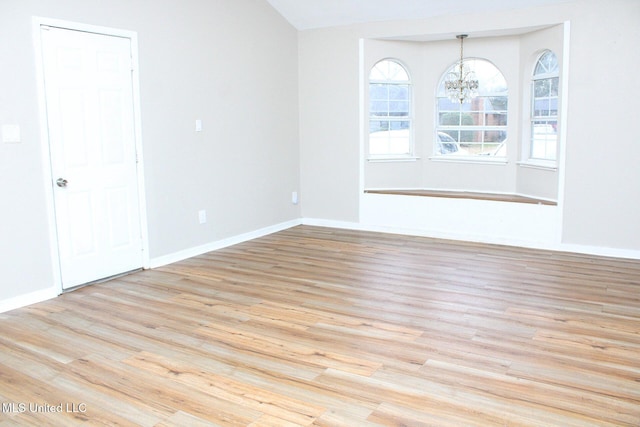 unfurnished room with light wood-type flooring, baseboards, and an inviting chandelier