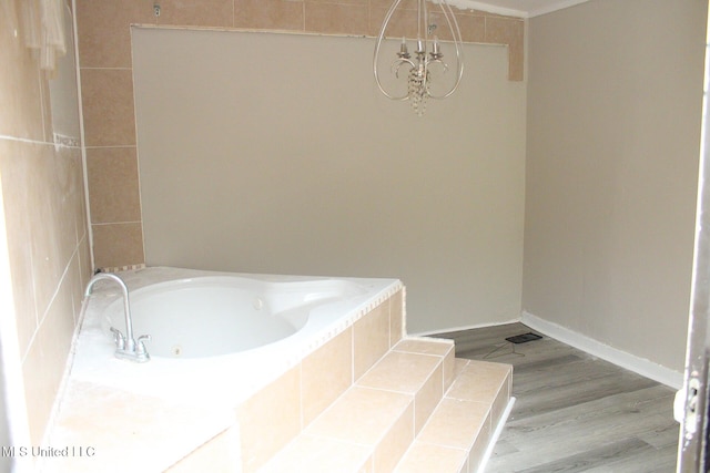 full bathroom featuring a washtub, wood finished floors, baseboards, tiled shower, and an inviting chandelier