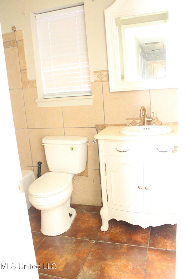 bathroom featuring toilet, tile walls, and vanity