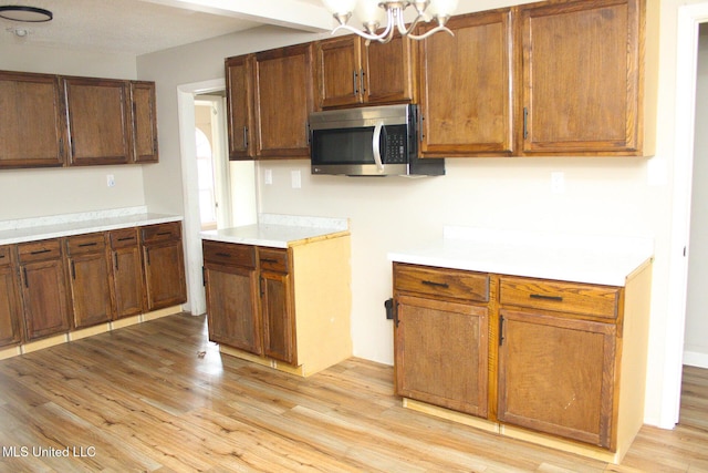 kitchen featuring light wood-style floors, light countertops, and stainless steel microwave