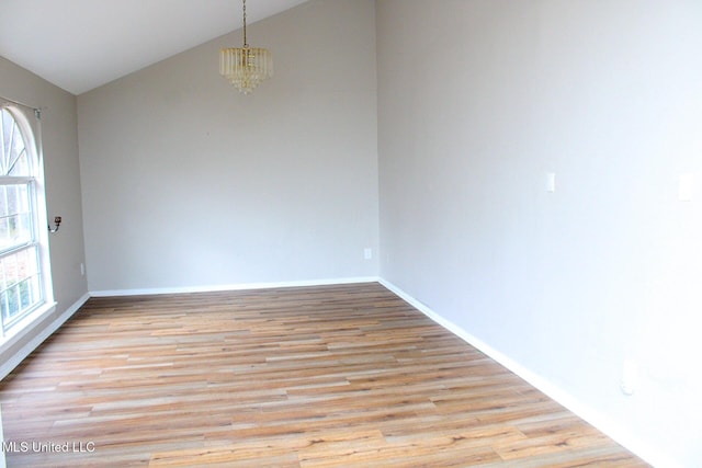 unfurnished room with a chandelier, light wood-type flooring, lofted ceiling, and baseboards