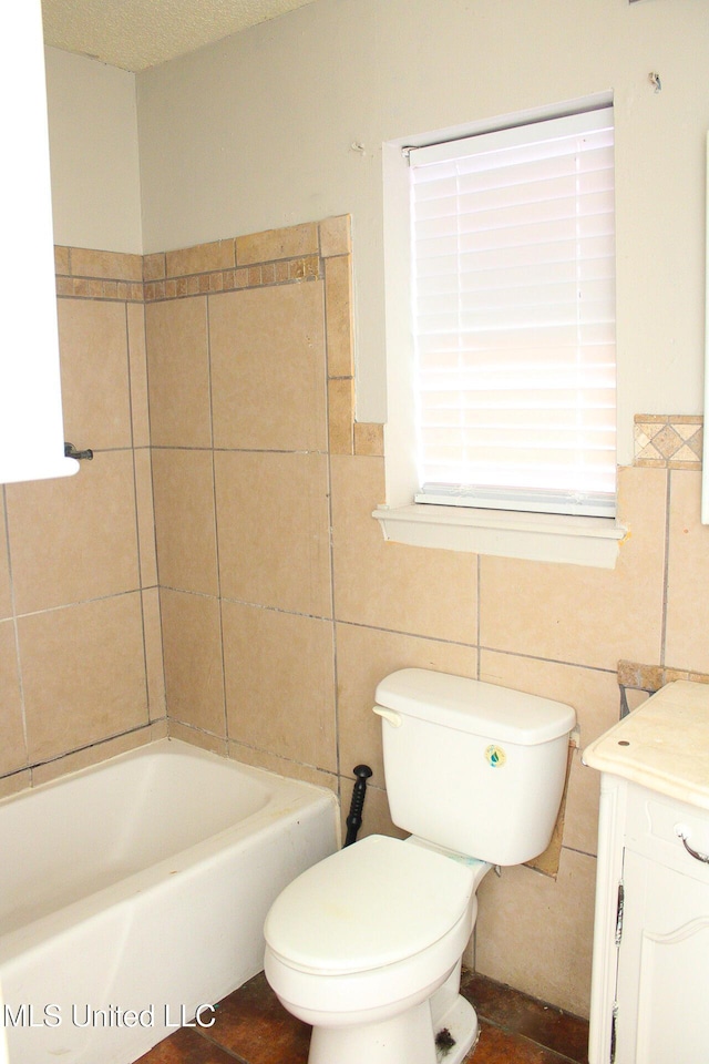 full bathroom featuring tile walls, toilet, a textured ceiling, vanity, and a tub