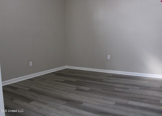 unfurnished room featuring baseboards and dark wood finished floors