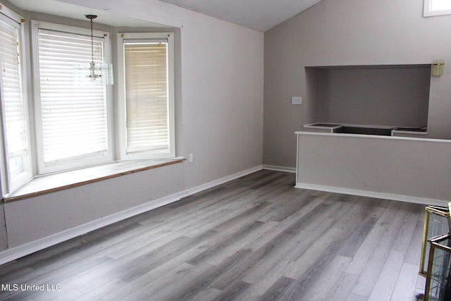 unfurnished living room featuring lofted ceiling, baseboards, and wood finished floors