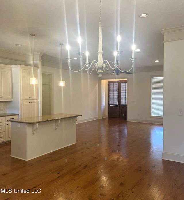 kitchen featuring a breakfast bar area, baseboards, dark wood-type flooring, open floor plan, and a chandelier