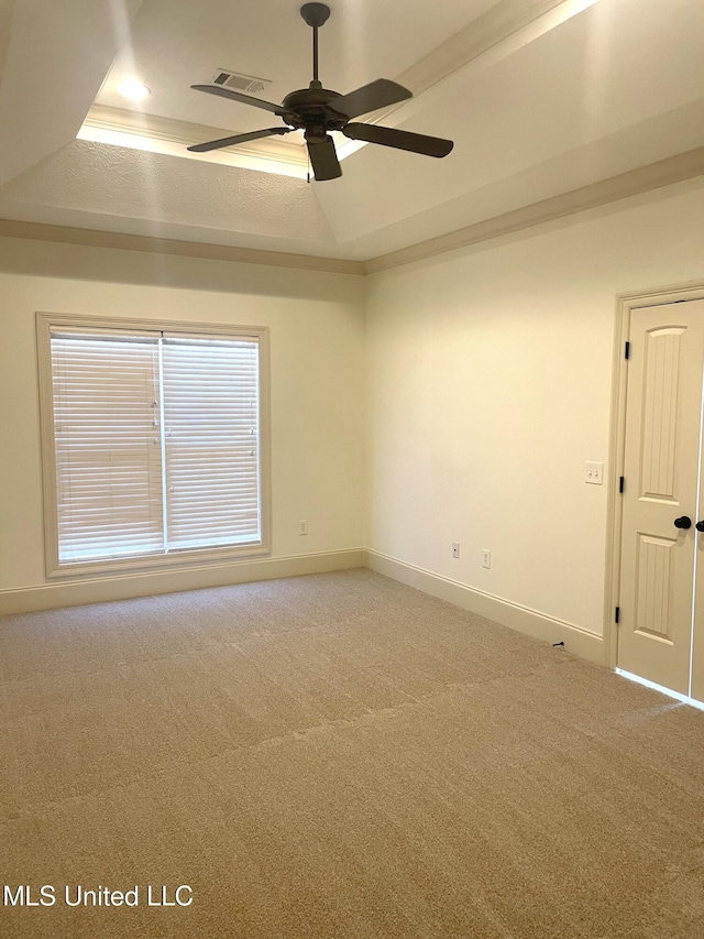 spare room featuring a tray ceiling, light carpet, baseboards, and a ceiling fan