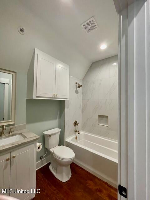 full bathroom featuring tiled shower / bath combo, wood-type flooring, lofted ceiling, toilet, and vanity