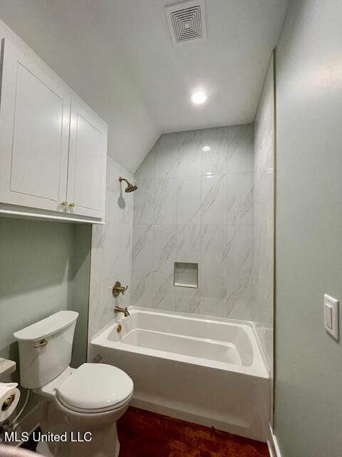 bathroom featuring toilet, tiled shower / bath combo, and vaulted ceiling