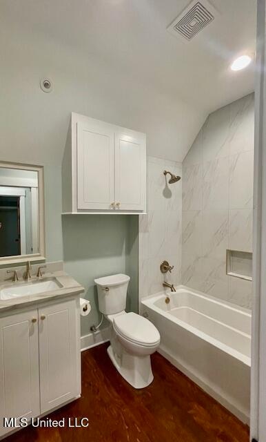 full bathroom featuring tiled shower / bath combo, wood-type flooring, lofted ceiling, toilet, and vanity