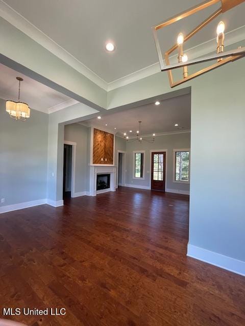 unfurnished living room with dark hardwood / wood-style flooring, an inviting chandelier, and ornamental molding