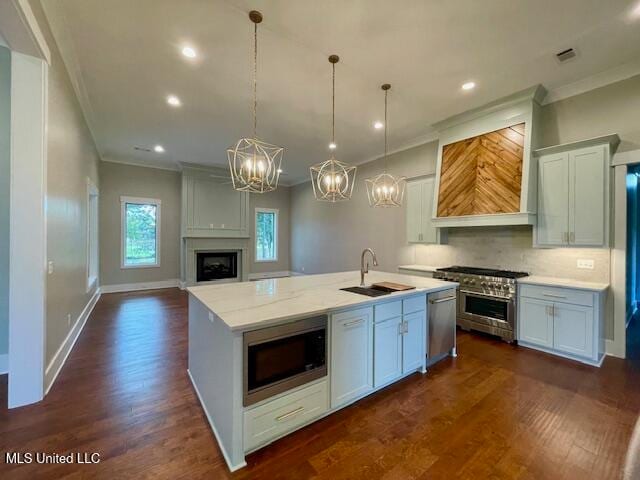 kitchen featuring stainless steel appliances, a kitchen island with sink, sink, decorative light fixtures, and dark hardwood / wood-style floors