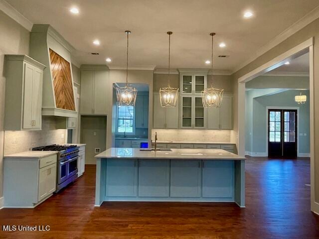 kitchen with pendant lighting, range with two ovens, sink, dark hardwood / wood-style floors, and an island with sink