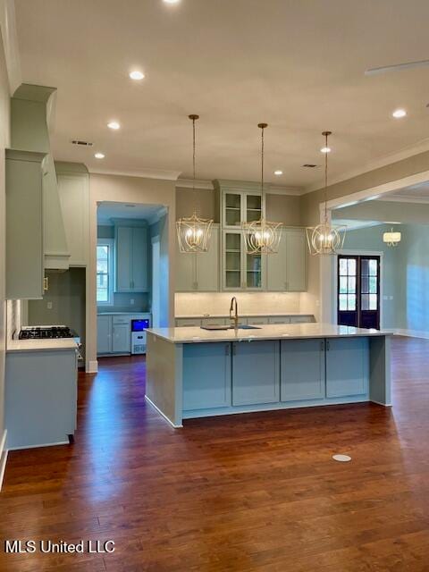 kitchen with pendant lighting, dark hardwood / wood-style floors, a large island with sink, and sink