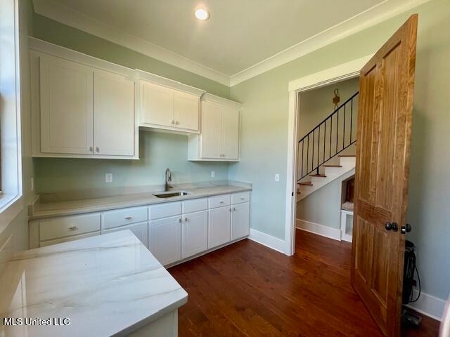 kitchen featuring white cabinets, ornamental molding, dark wood-type flooring, and sink