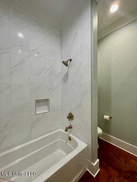 bathroom featuring hardwood / wood-style floors, toilet, and tiled shower / bath