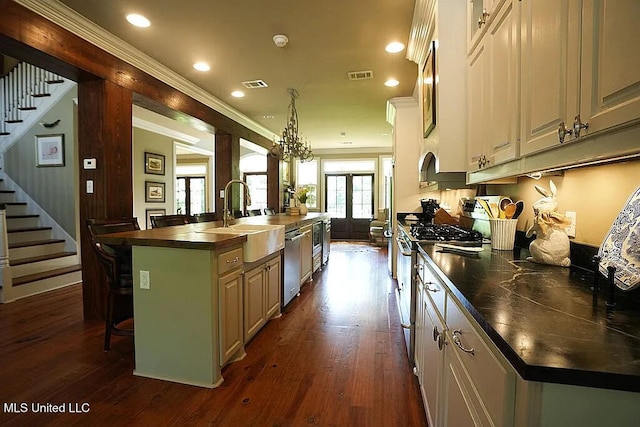 kitchen with visible vents, stainless steel appliances, a sink, and a kitchen island with sink