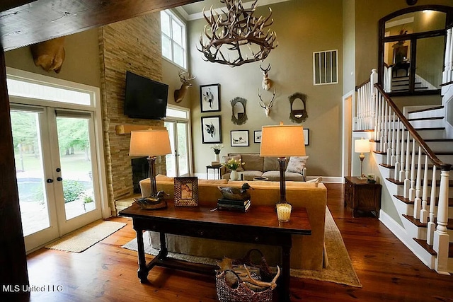 living room featuring a towering ceiling, french doors, wood finished floors, and visible vents