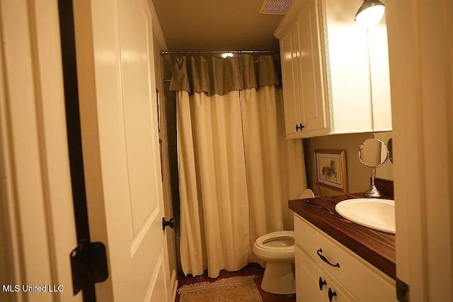 full bathroom with toilet, curtained shower, vanity, and visible vents