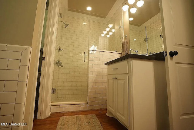 bathroom with a stall shower, wood finished floors, and tile walls