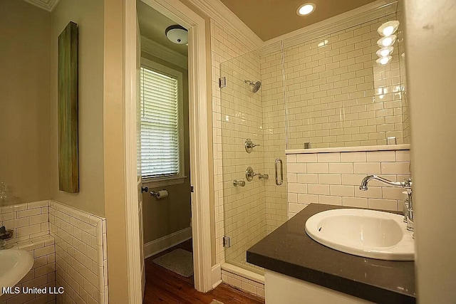 bathroom featuring a shower stall, tile walls, a sink, and wood finished floors