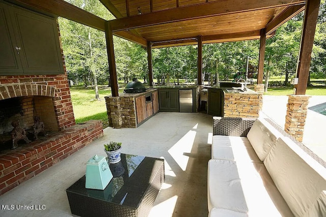 view of patio with a sink, an outdoor living space with a fireplace, exterior kitchen, and a grill