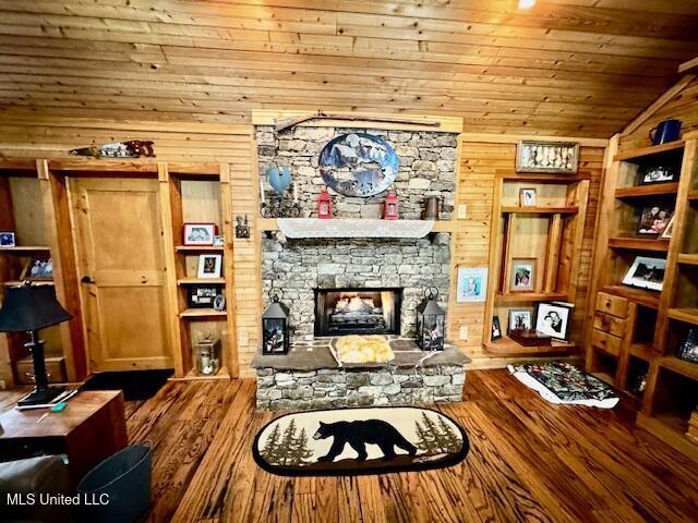 living room with wooden walls, wooden ceiling, wood finished floors, vaulted ceiling, and a fireplace