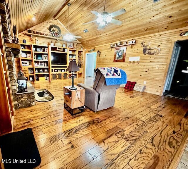 living room featuring lofted ceiling, ceiling fan, wooden walls, wood finished floors, and wood ceiling