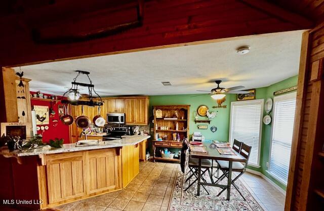 kitchen featuring stainless steel microwave, a peninsula, light countertops, a sink, and range with electric stovetop