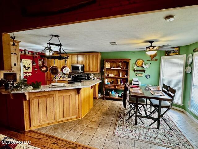 kitchen with light countertops, stainless steel microwave, range with electric stovetop, and a peninsula