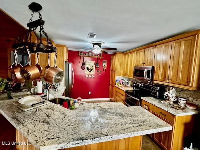 kitchen with stainless steel appliances, light stone counters, and visible vents