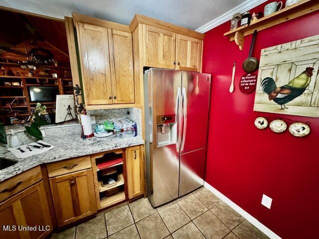 kitchen featuring light tile patterned floors, baseboards, stainless steel fridge with ice dispenser, ornamental molding, and light stone countertops