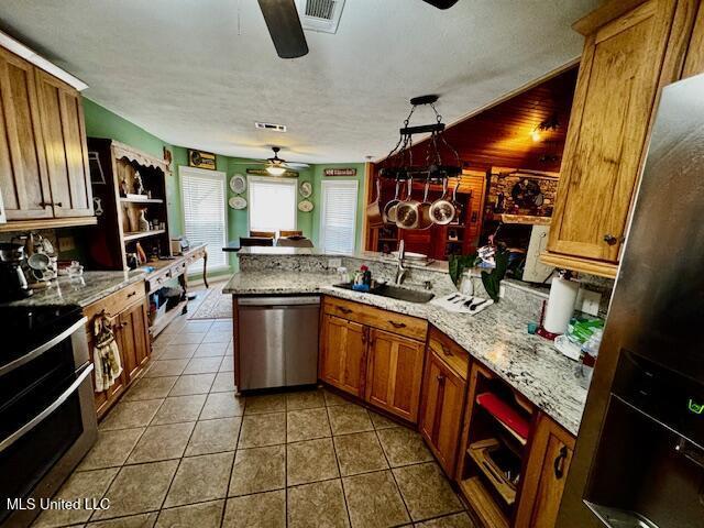 kitchen with stainless steel appliances, visible vents, a sink, a peninsula, and tile patterned floors