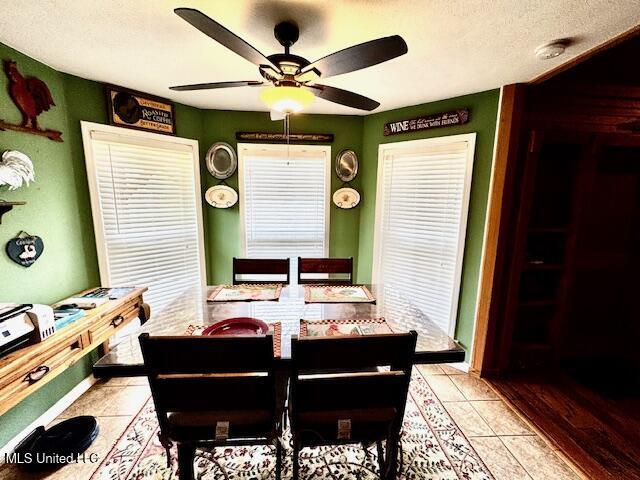 dining space featuring light tile patterned floors, ceiling fan, and a textured ceiling