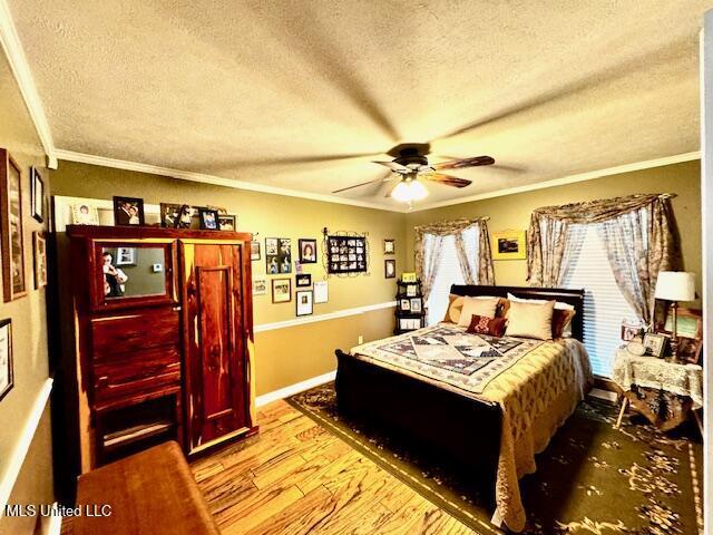 bedroom featuring light wood-type flooring, crown molding, a textured ceiling, and baseboards