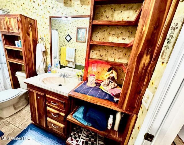 bathroom with toilet, wallpapered walls, tile patterned flooring, and vanity