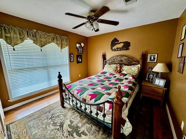 bedroom featuring ceiling fan, wood finished floors, and visible vents