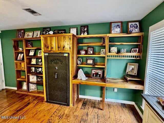 interior space with wood finished floors, built in study area, visible vents, and baseboards