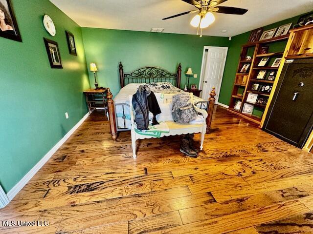 bedroom with wood finished floors, a ceiling fan, and baseboards