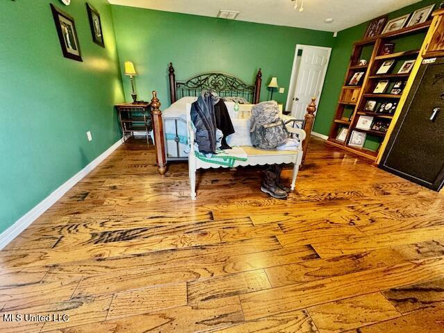 bedroom with visible vents, baseboards, and wood finished floors