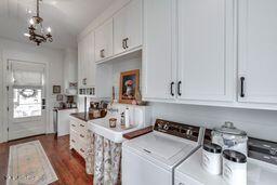 381 Parkinson Rd, Flora, MS 39071 - washroom with washing machine and clothes dryer, a chandelier, and dark wood finished floors