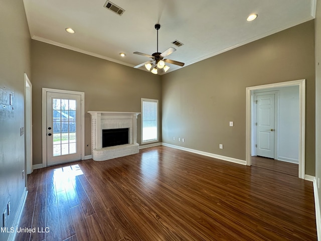 unfurnished living room featuring ceiling fan, crown molding, dark wood-type flooring, and a brick fireplace